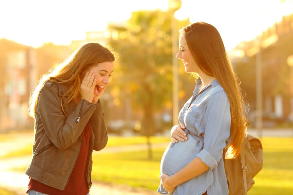 Chica asombrada mirando la barriga de su amiga embarazada