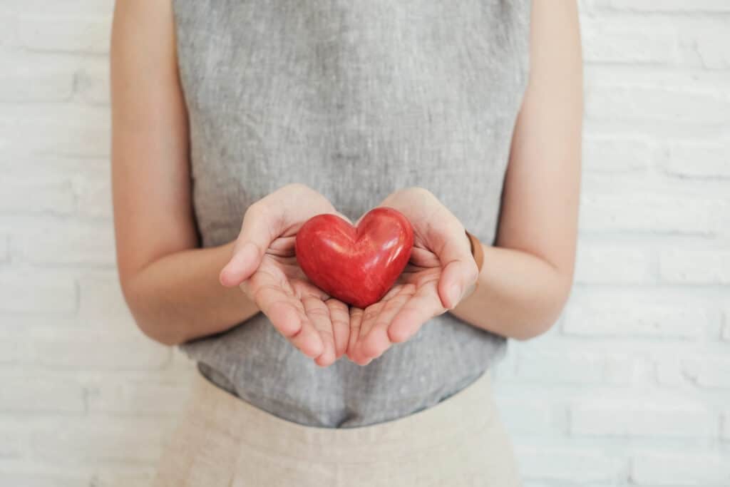 mujer sosteniendo corazón rojo, seguro de salud, concepto de donación benéfica